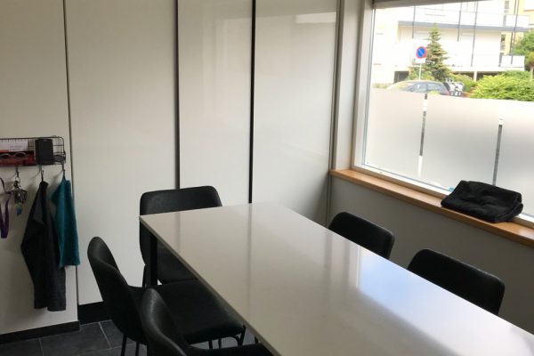 Strakke wand met grote koelkast en diepvries. Greeplijsten hebben we zwart laten poedercoaten
